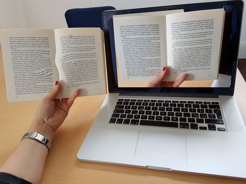 Figure 1: A possible implementation of the technology:  A computer helps a user with distorted vision to read a book by improving their visual perception.